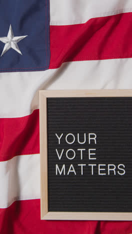 Vertical-Video-Of-Sign-Reading-Your-Vote-Matters-Lying-On-US-Stars-And-Stripes-Flag-For-American-Election-2024-1